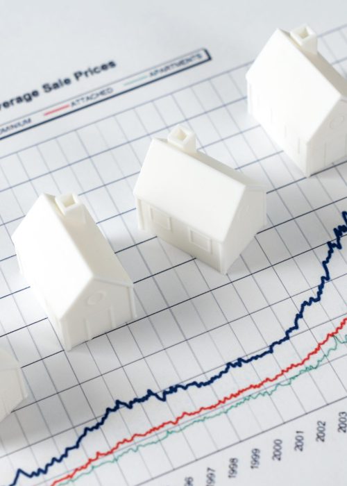 White miniature house models on graph indicating growth in real estate prices market